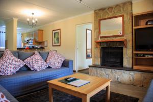 a living room with a blue couch and a fireplace at Gooderson Leisure Riverbend Chalets Self Catering in Drakensberg Garden