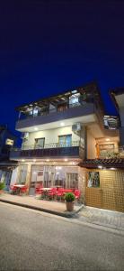 a building with red tables and chairs in front of it at Nako Guest House bar&restaurants in Përmet