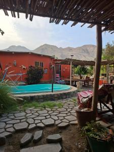 a swimming pool in a yard with a red building at Ecoalbergue Retablos Perú Habitación YING YANG in Lunahuaná