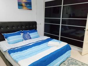 a bed with blue and white blankets and pillows at Aura Bluewave Beach House, Chenang in Pantai Cenang +14 photos