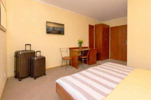 a hotel room with a bed and a desk with two suitcases at Pensjonat Marynarski - Apartamenty in Darlowko +34 photos