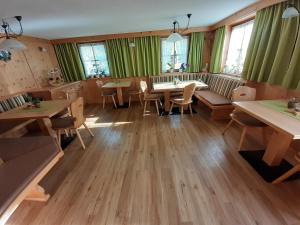 a restaurant with tables and chairs and green curtains at Haus Bödele in Sankt Leonhard im Pitztal +44 photos