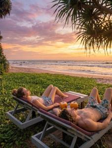 a couple of people laying on a picnic table on the beach at La Brisa By Harry Beach Villa in Dickwella