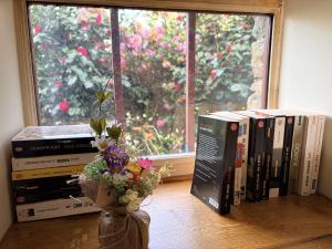 a vase of flowers sitting on a table next to books at AppartCosy 27 Epine in Châteaubourg