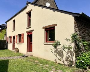a white house with red windows and a clock at AppartCosy 27 Epine in Châteaubourg