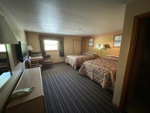 a hotel room with two beds and a desk at Budget Inn - Cambridge in Fairdale