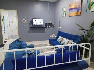 a living room with a blue couch and a tv at Aura Bluewave Beach House, Chenang in Pantai Cenang