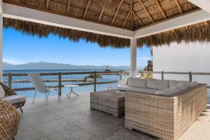 a patio with a couch and chairs and a view of the ocean at Bahiban Residences Oceanfront by Monyxbnb in Cruz de Huanacaxtle