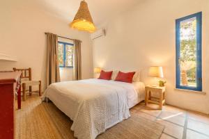 a bedroom with a white bed with red pillows at Villa Bambu in Charneca +42 photos