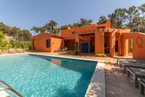 a villa with a swimming pool in front of a house at Villa Bambu in Charneca