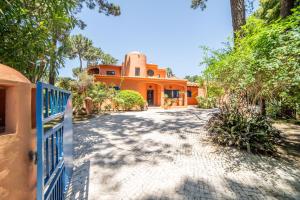 an orange house with a fence in front of a driveway at Villa Bambu in Charneca