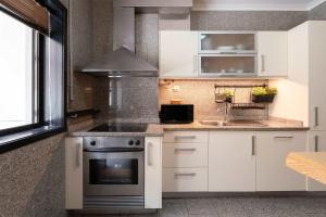 a kitchen with white cabinets and a stove at Oceanfront Views & Modern Elegance by HostWise in Vila do Conde