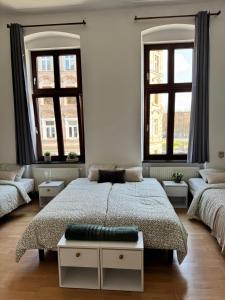 a bedroom with a large bed and two windows at Apartament przy Kościele in Świdnica