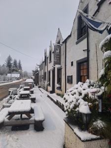 a snow covered street with benches and a building at The Inn at Strathyre in Strathyre