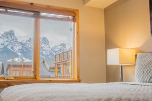 a bedroom with a window with a mountain view at White Spruce Condo by Canadian Rockies Vacation Rentals in Canmore