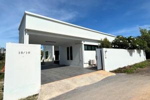 a white house with a gate in front of it at Cha-am Pool Villa in Ban Bo Prakhon