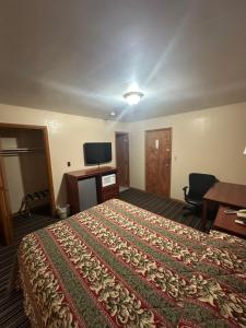 a hotel room with a bed and a desk and a tv at Budget Inn - Cambridge in Fairdale