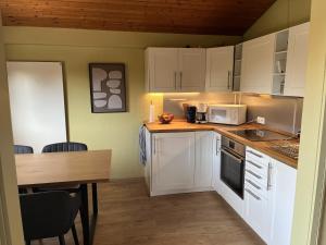 a kitchen with white cabinets and a table with a microwave at DeichLand117 in Butjadingen