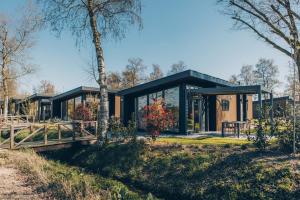 a house with glass walls and a tree at De Leughte in Renswoude
