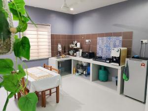 a kitchen with a counter and a table and a refrigerator at Aura Bluewave Beach House, Chenang in Pantai Cenang