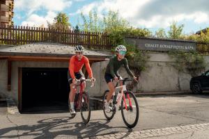 two men riding bikes in front of a garage at Chalet RoyAlp Hôtel & Spa in Villars-sur-Ollon
