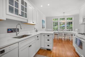 a white kitchen with white cabinets and a wooden floor at Captain's Row: Pool, Tennis Chatham Charm in Chatham