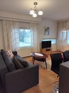 a living room with a couch and a table and a tv at Varakoti Helmi in Loimaa