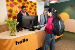 a woman standing in front of a hello reception desk at Meco Hotel in Boston