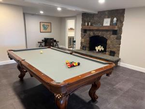 a pool table in a living room with a fireplace at Relax by the Lake: Private Beach Views in Centerville