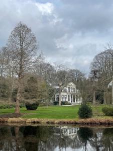 a large white house with a pond in front of it at De Fugelsang in Jonkersland