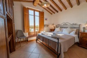 a bedroom with a bed and a chair and a window at Poggio del Raglio in Trequanda
