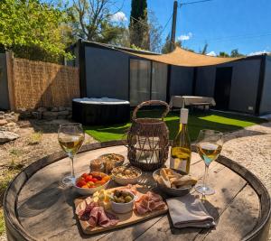 a table with a tray of food and glasses of wine at Bungalow jacuzzi & jardin privatif séjour détente au soleil in La Crau