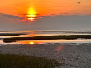 a sunset over the water with the sun setting at Beach Glass—Space, Fun Furry Friends Welcome in Brewster +57 photos