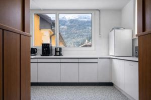 a kitchen with white cabinets and a window at Casa Arcobaleno in Airolo