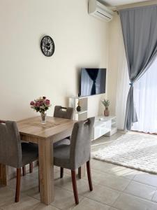 a dining room table with chairs and a clock on the wall at Apartments Sofia in Kotor