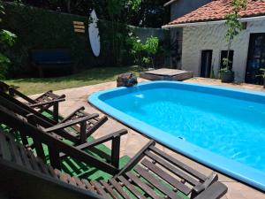 a swimming pool with two chairs and a dog in it at Pousada Toa Toa Em Pipa in Pipa