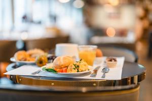 a tray with two plates of food and a glass of orange juice at HENRI Hotel Cuxhaven in Cuxhaven