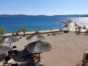 a group of people on a beach with umbrellas at Regina Mobile Home 3 Bedrooms, 100m to Beach, Family Friendly in Sveti Filip i Jakov +19 photos