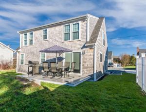a house with a patio with chairs and an umbrella at Cape Cod Home—Deck, Near Canal Bike Path in Sandwich