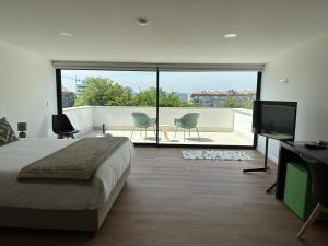 a bedroom with a bed and a balcony with a television at Loft Azeméis in Oliveira de Azemeis