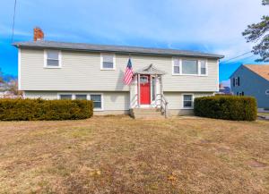 a white house with a red door and an american flag at Family Cape Escape—Beach, Boardwalk Game Room in Sandwich