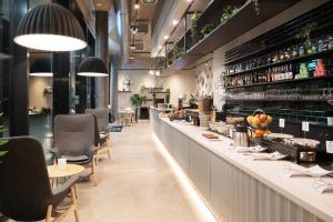 a restaurant with a long counter with chairs and tables at B&B HOTEL Basel in Basel
