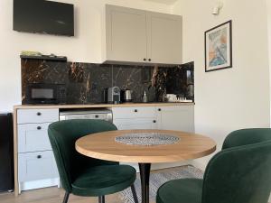 a kitchen with a wooden table and green chairs at Madi Apartamenty in Sandomierz +30 photos