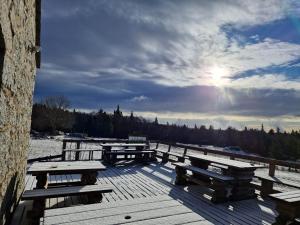 a group of picnic tables on a wooden deck with the sun at Auberge du Mas de la Barque in Villefort