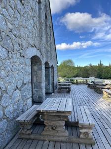 a wooden deck with benches next to a stone wall at Auberge du Mas de la Barque in Villefort