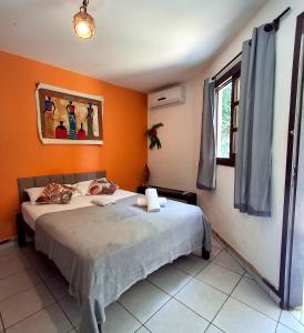 a bedroom with a bed and an orange wall at Pousada Toa Toa Em Pipa in Pipa