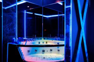 a bath tub in a room with blue lights at BDSM room Bydgoszcz z jacuzzi dużym tarasem i Balią zewnętrzną in Bydgoszcz
