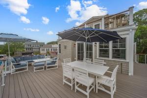 a deck with a table and chairs and an umbrella at Happy As A Clam in Chatham