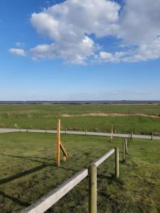 a view of a field with wooden posts and a road at Ferienhaus Petersen in Langeneß +4 photos