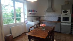 a kitchen with a table with a vase of flowers on it at Le Couvent in Lagardelle
